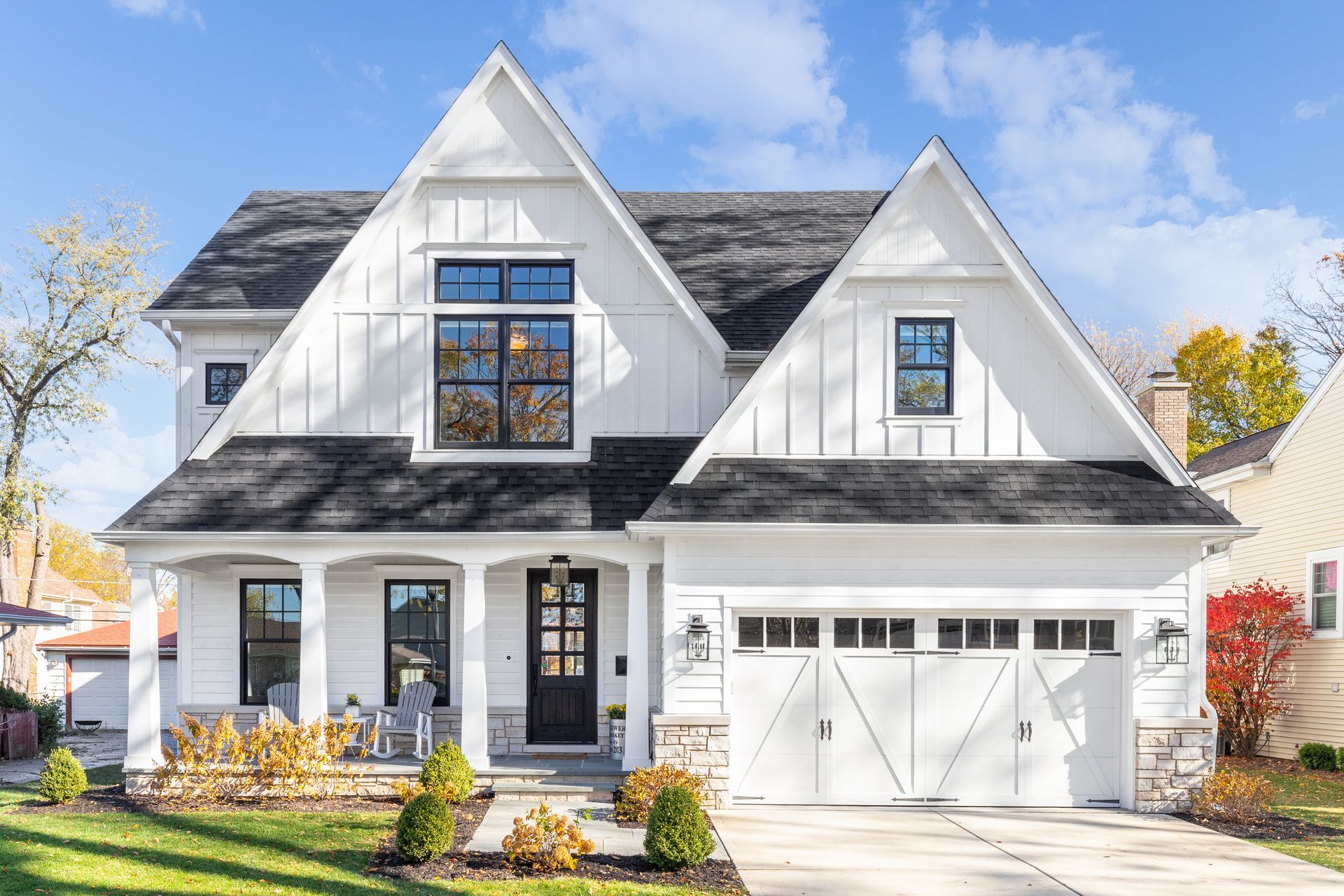 a white house with a black roof and a black garage door .