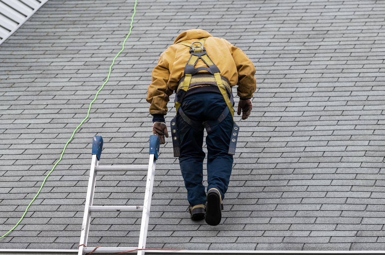 a man is walking up a ladder on a roof .