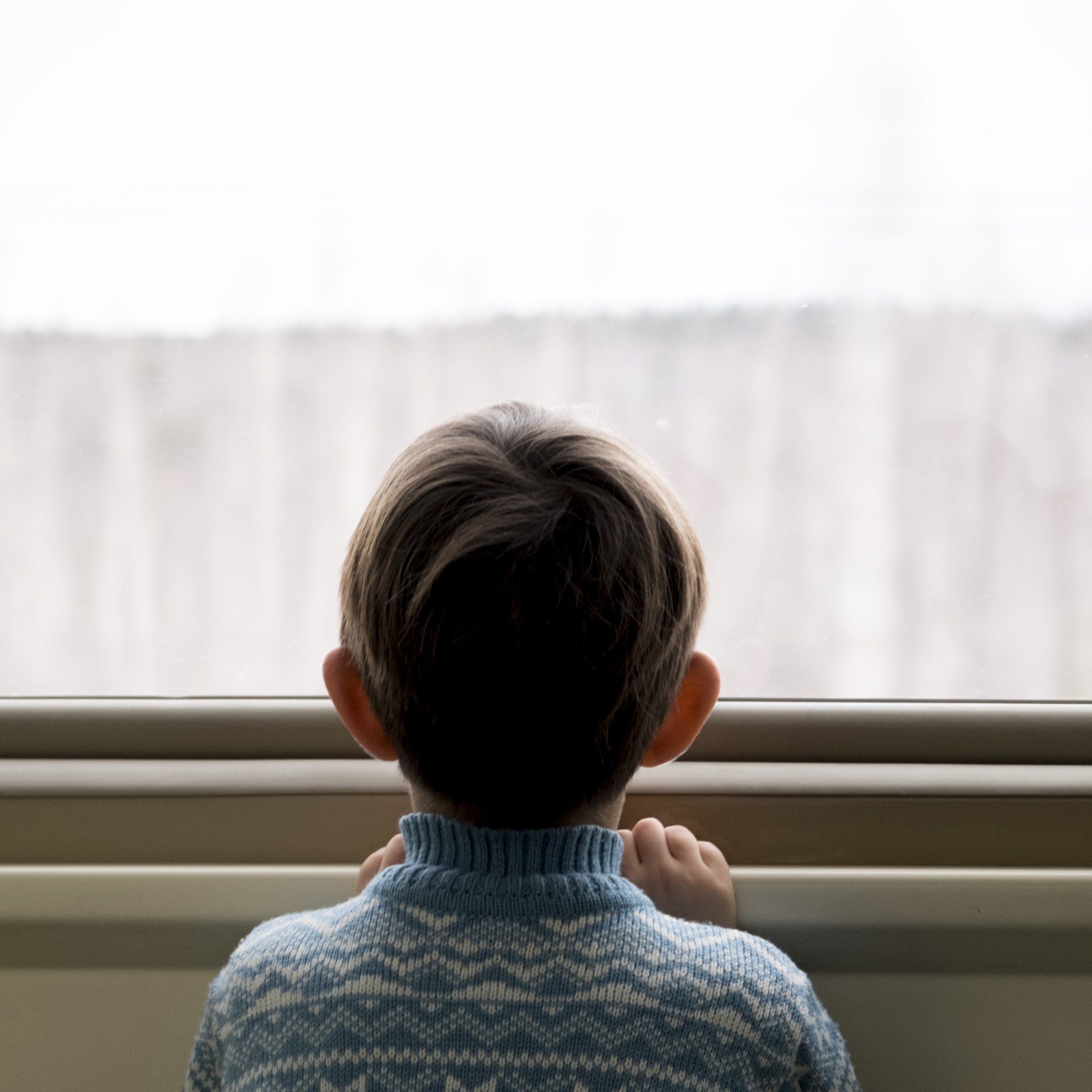 a small boy looking out from a window