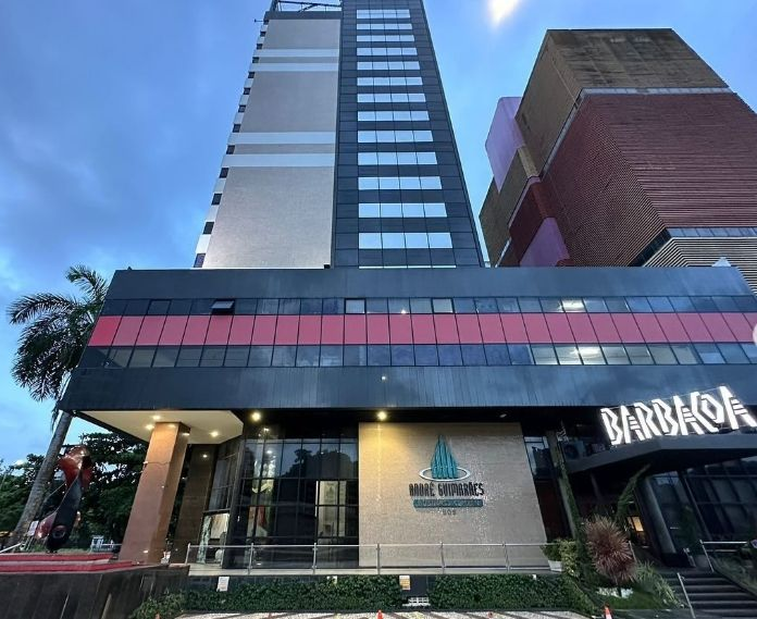 Prédio moderno de vários andares com um restaurante no térreo e uma placa com a inscrição “BARBACOA”.