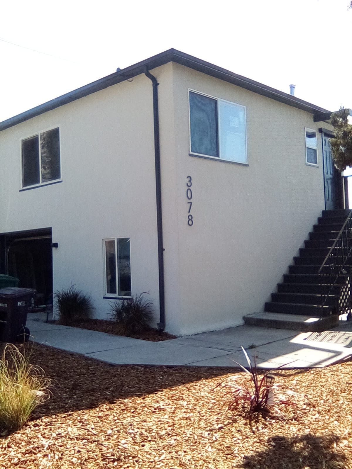 Two-story tan building with a stairwell, window, and address 