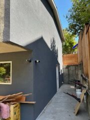 Gray building exterior with a ramp and wooden fence.