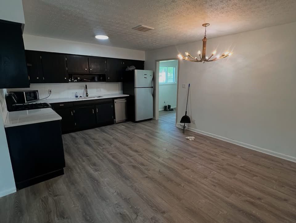 Kitchen with black cabinets, white countertops, stainless steel refrigerator, and chandelier.