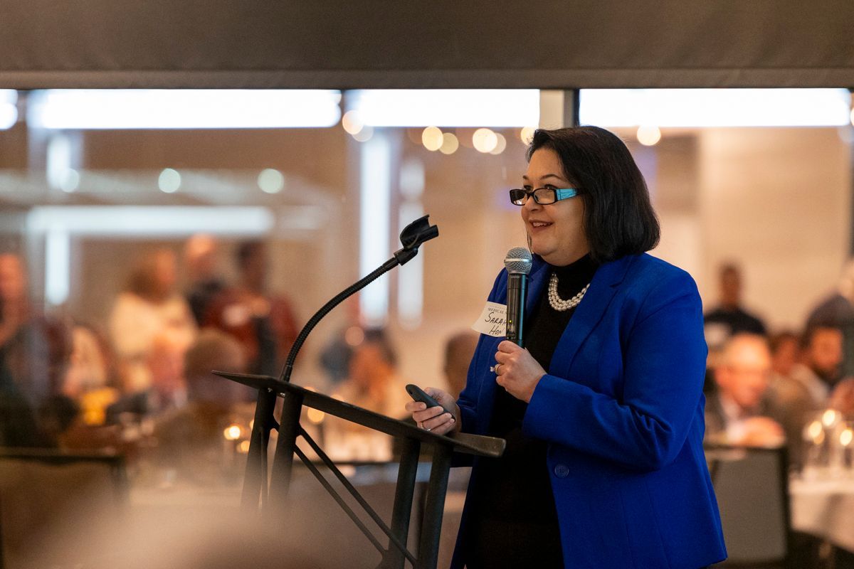 A group of people are standing around a table talking to each other at a party.