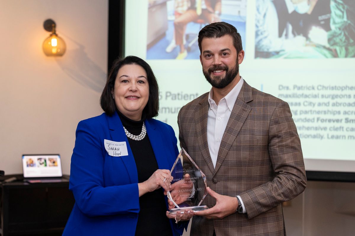 A bald man wearing glasses and a white coat and tie