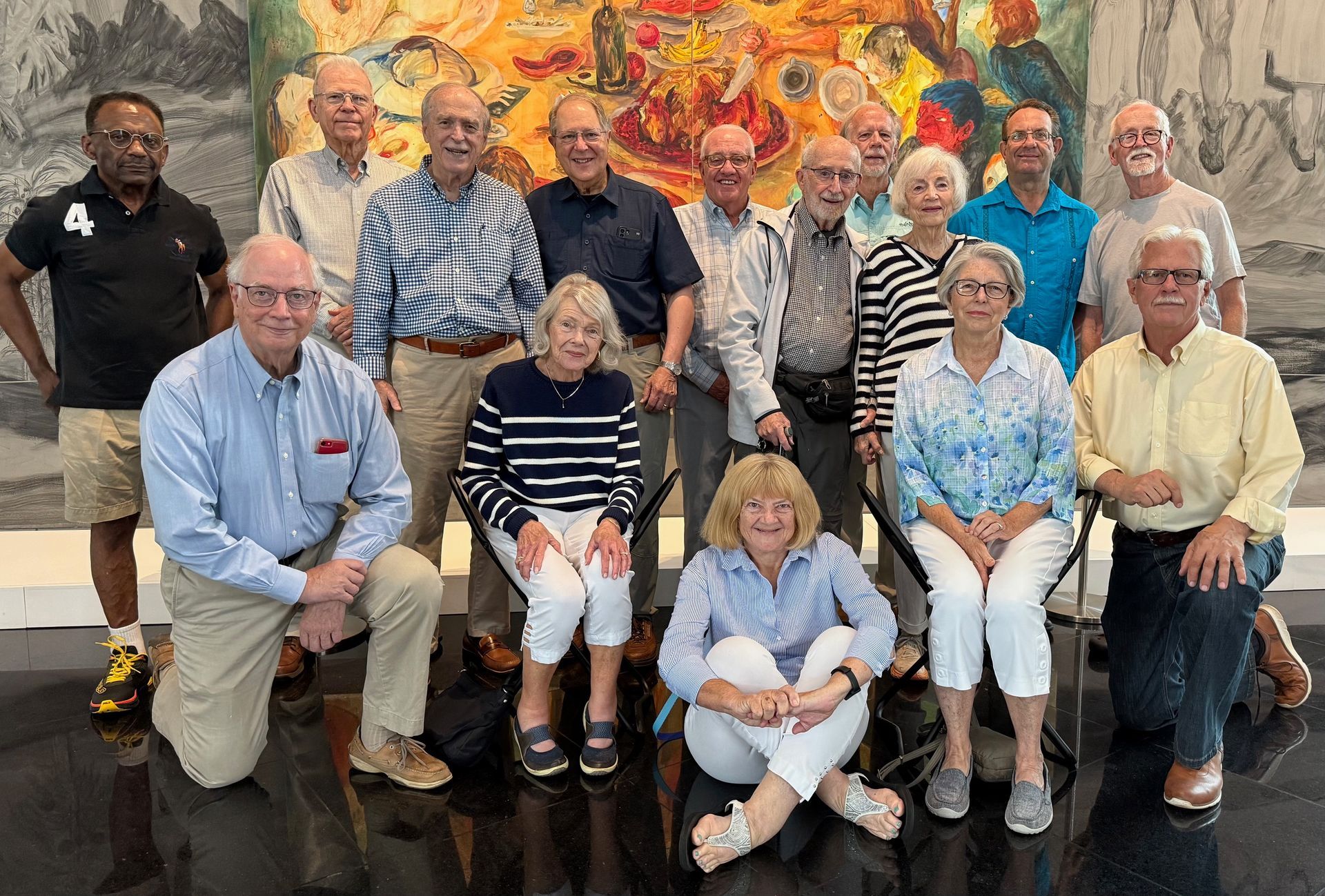 A group of people are posing for a picture in front of a painting.
