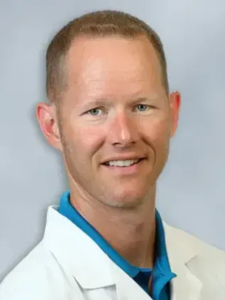 A woman in a black jacket and white turtleneck is smiling for the camera.