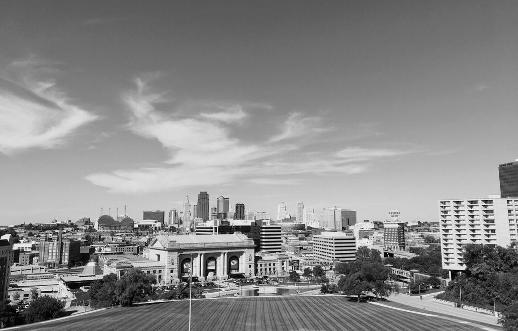 A black and white photo of the Kansas City skyline with a field in the foreground.