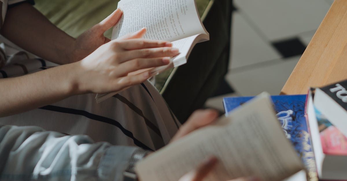 A person is sitting at a table reading a book.