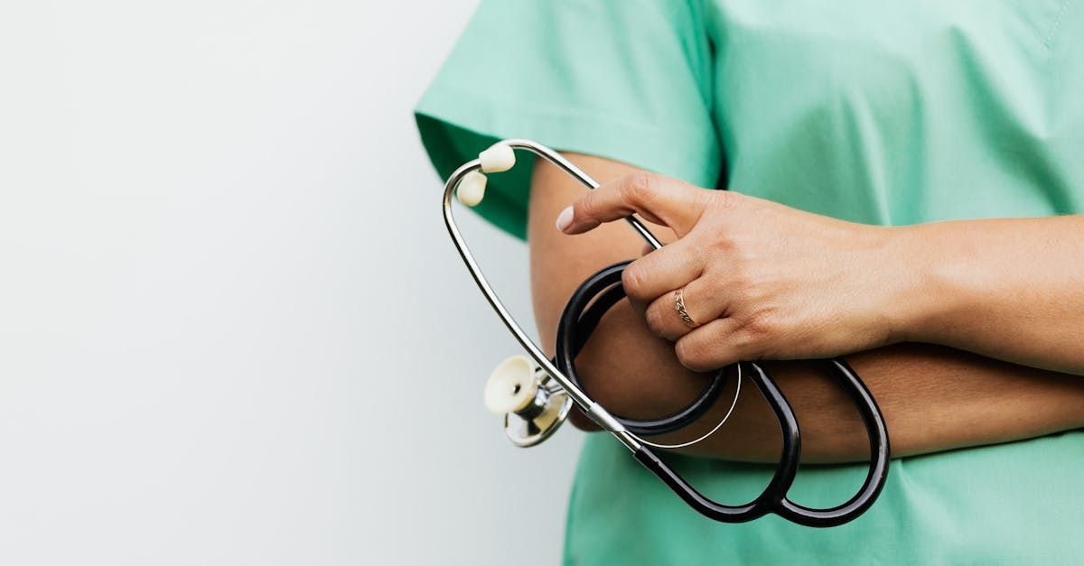 A nurse is holding a stethoscope with her arms crossed.