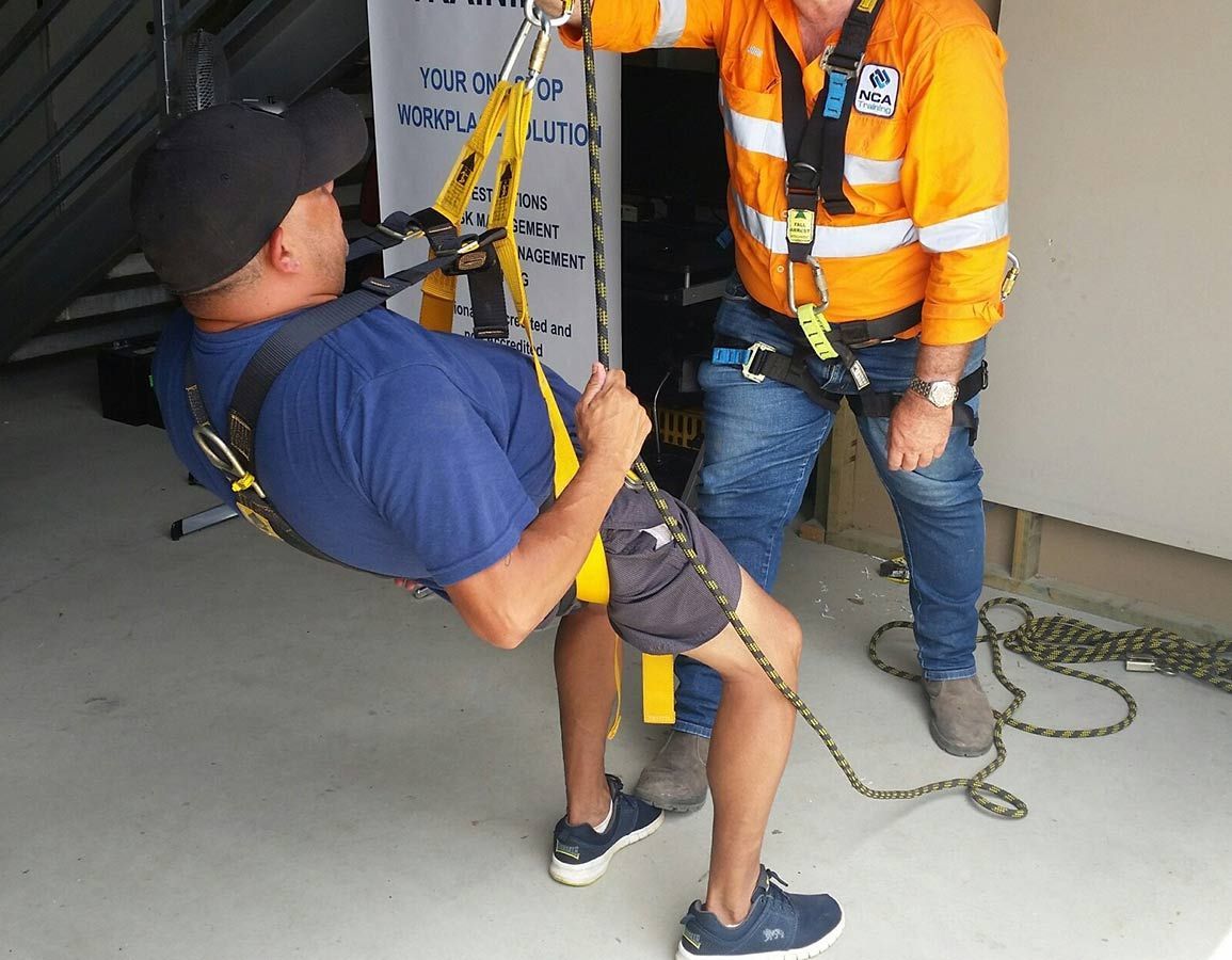 A Man In A Blue Shirt Is Being Helped Up By A Man In An Orange Shirt — NCA Consulting Pty Ltd in Alstonville, NSW