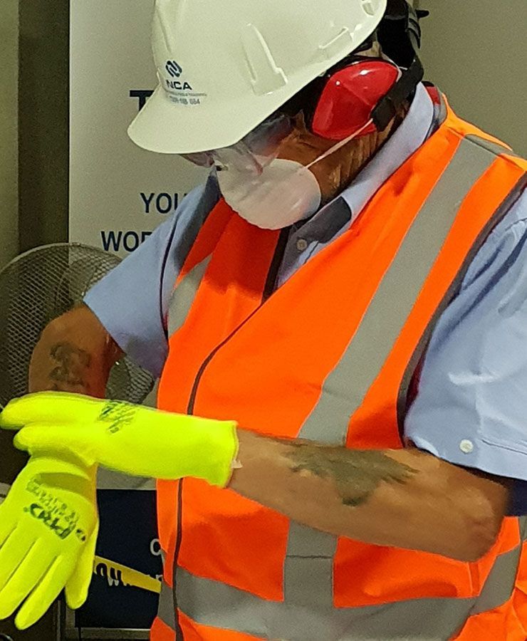 A woman Wearing A Hard Hat And Safety Vest Is Putting On Yellow Gloves — NCA Consulting Pty Ltd in Alstonville, NSW