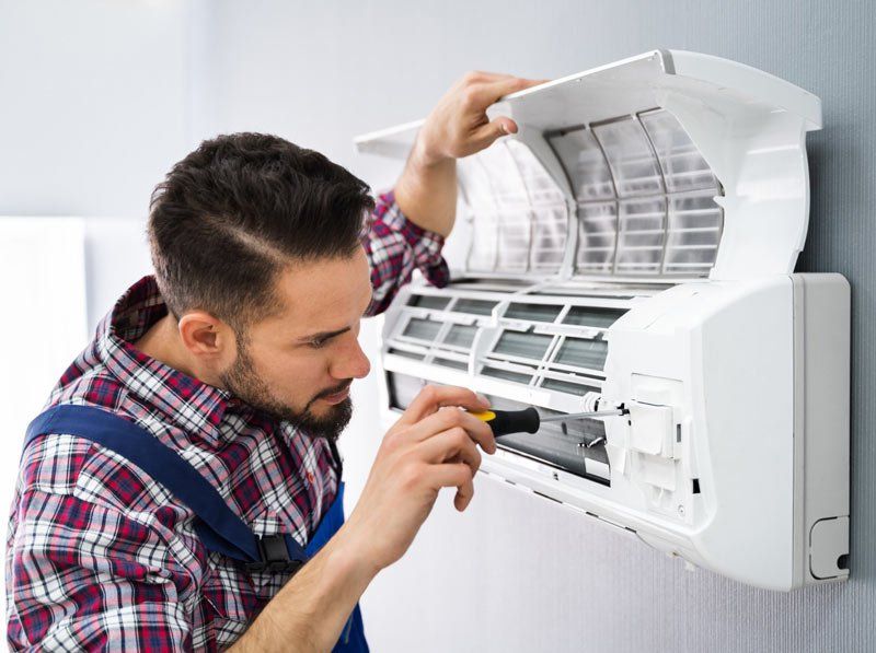 a man is fixing an air conditioner with a screwdriver .