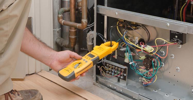 a man is working on an air conditioner with a clamp meter .