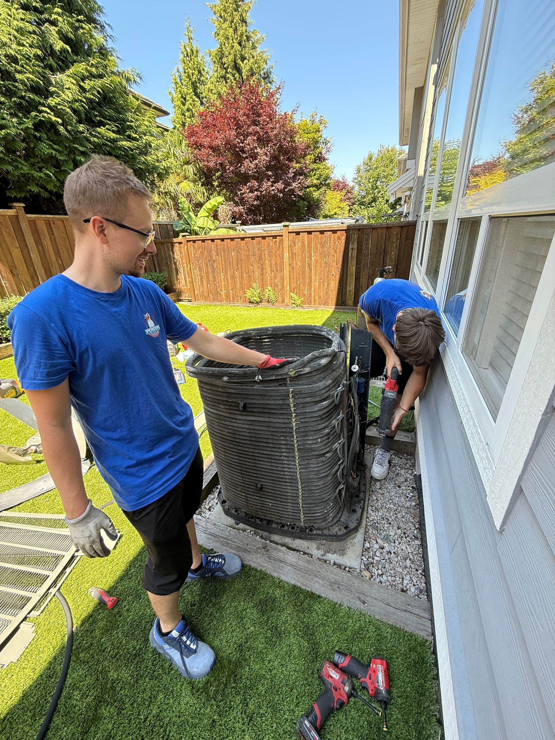 Two Penguin HVAC employees installing new air conditioner