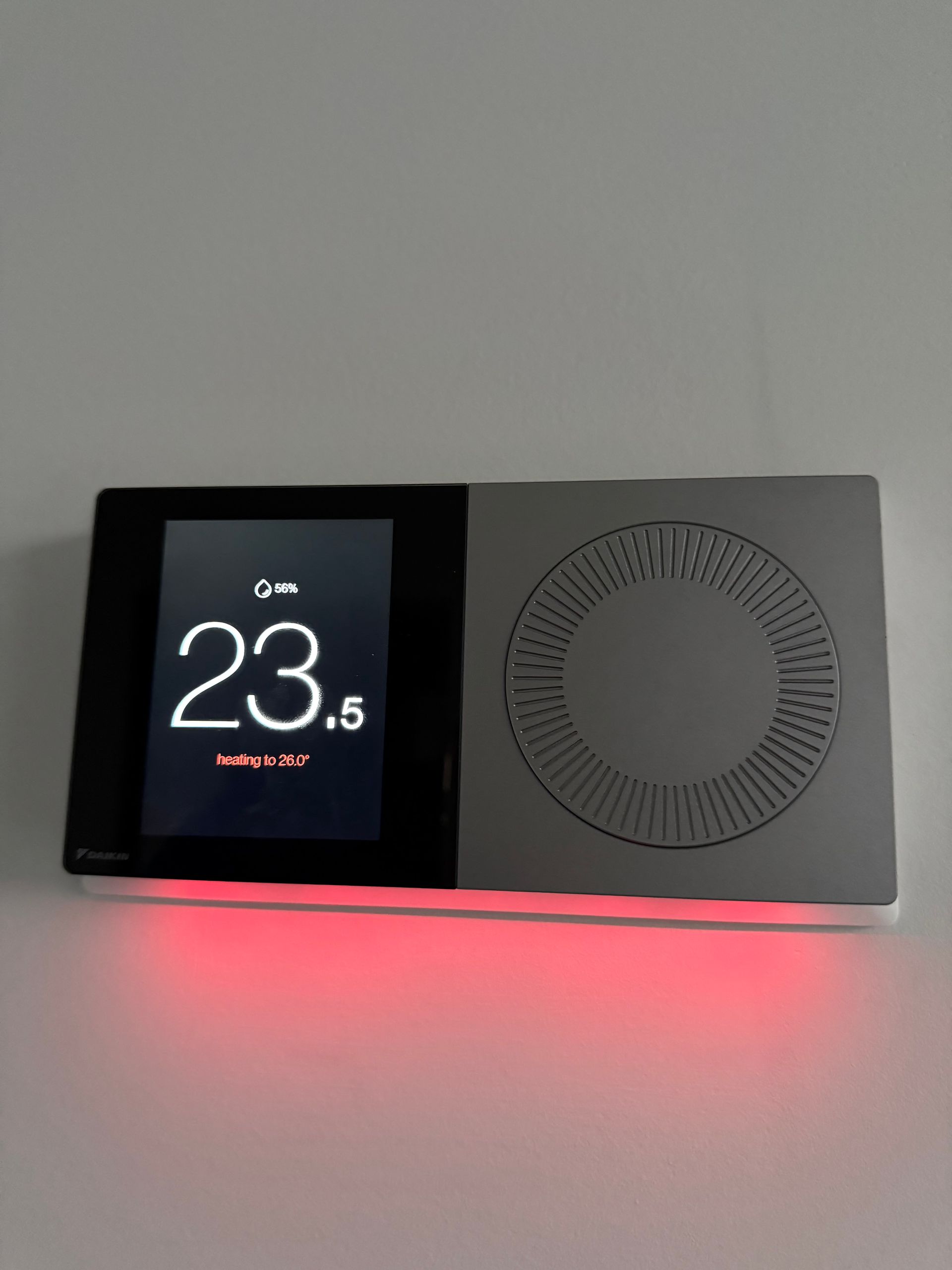 Black and gray thermostat showing 23.5 degrees Celsius with a red light on the bottom.