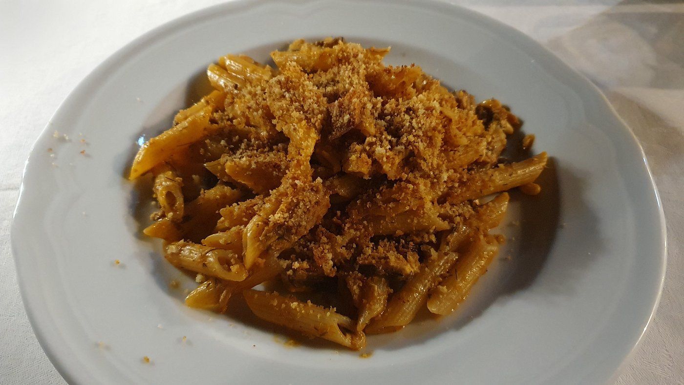 Piatto di pasta al sugo di pomodoro con formaggio grattugiato su un piatto bianco.