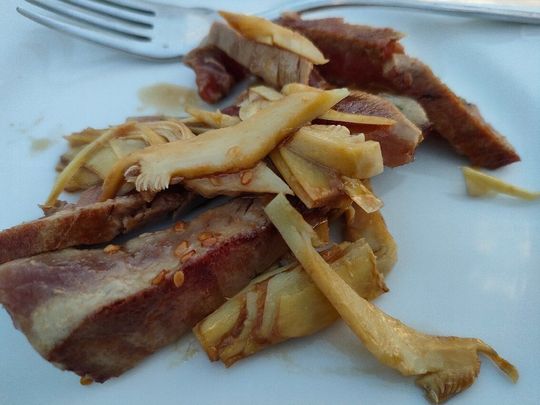 Carne arrosto a fette con cipolle su un piatto bianco con forchetta