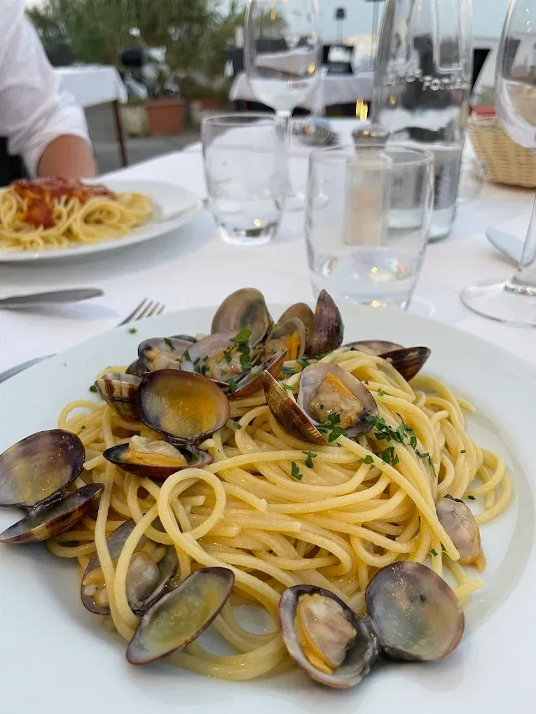 Piatto di spaghetti alle vongole su un tavolo bianco in un ristorante all'aperto