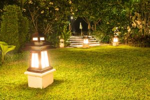 Lit garden path with lanterns and steps leading to a dark archway at night