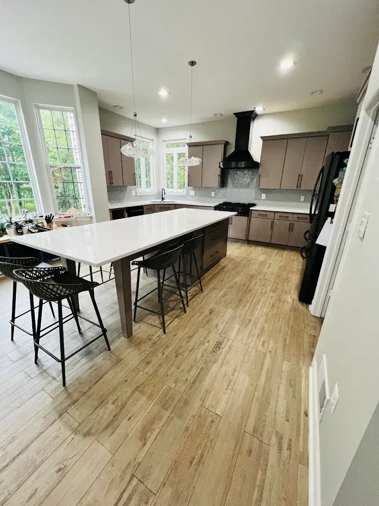 Modern kitchen with large island, bar stools, wood floors, and stainless appliances