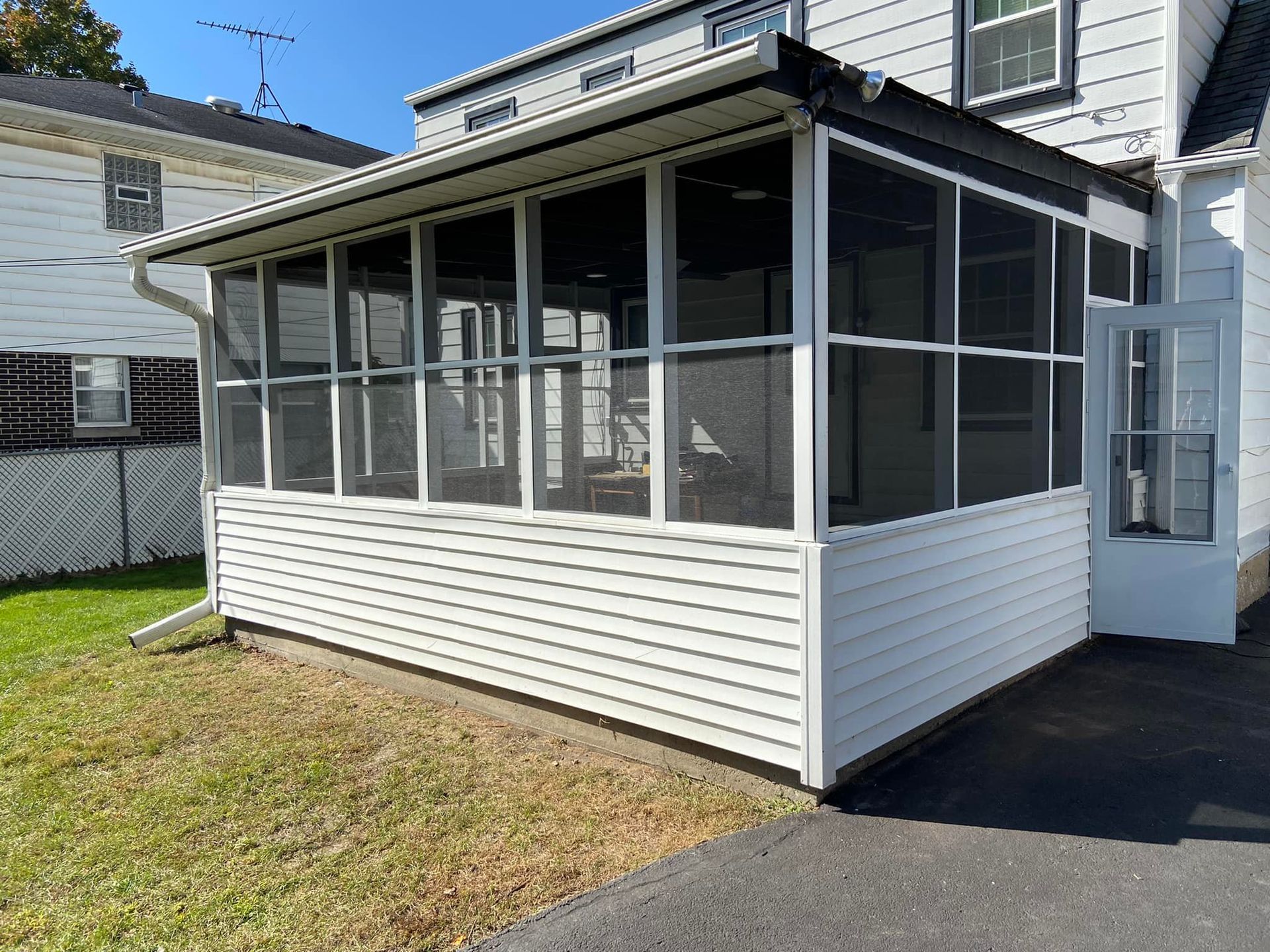 A screened in porch on the side of a house.