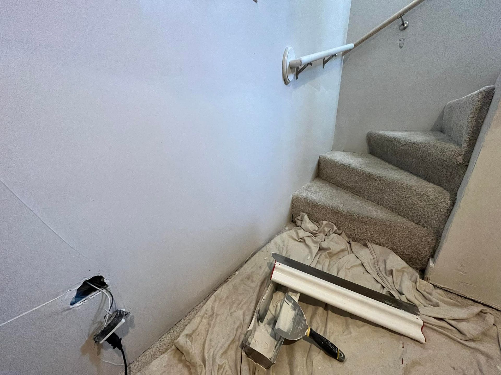 A staircase is being painted in a room with tools on the floor.
