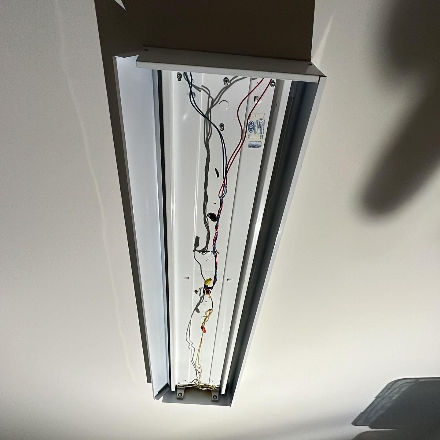 A light fixture is hanging from the ceiling with wires coming out of it.