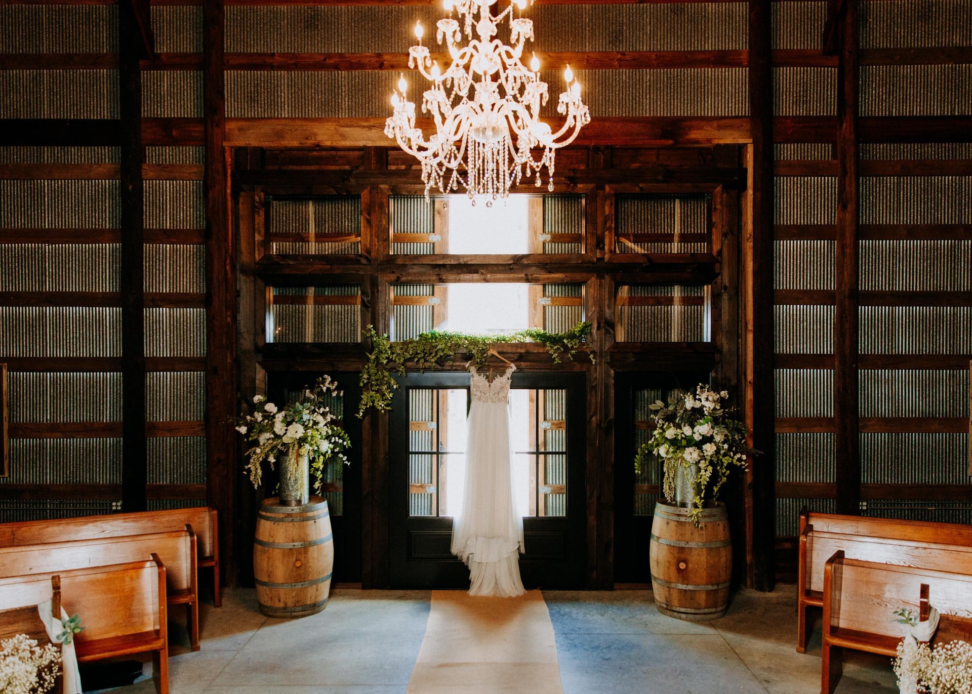Elegant library aisle with bookshelves, chandelier, wooden benches, and floral arrangements at the doorway