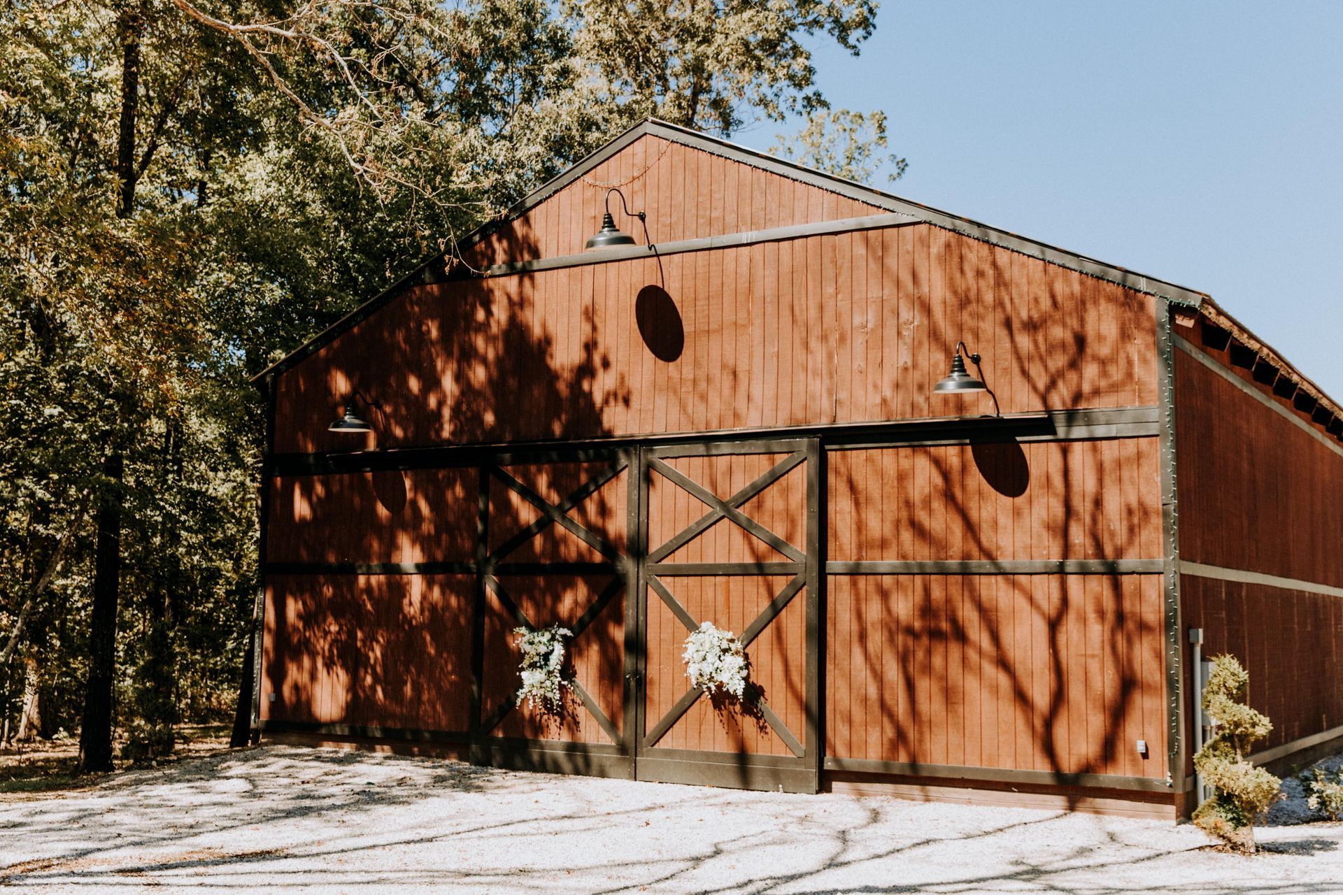Red barn with wooden doors and a white star on the front, set among trees in bright daylight