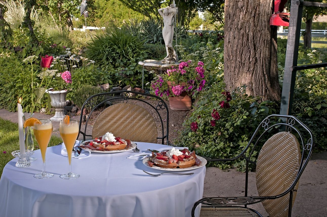 A table with two plates of food and two glasses of orange juice on it.