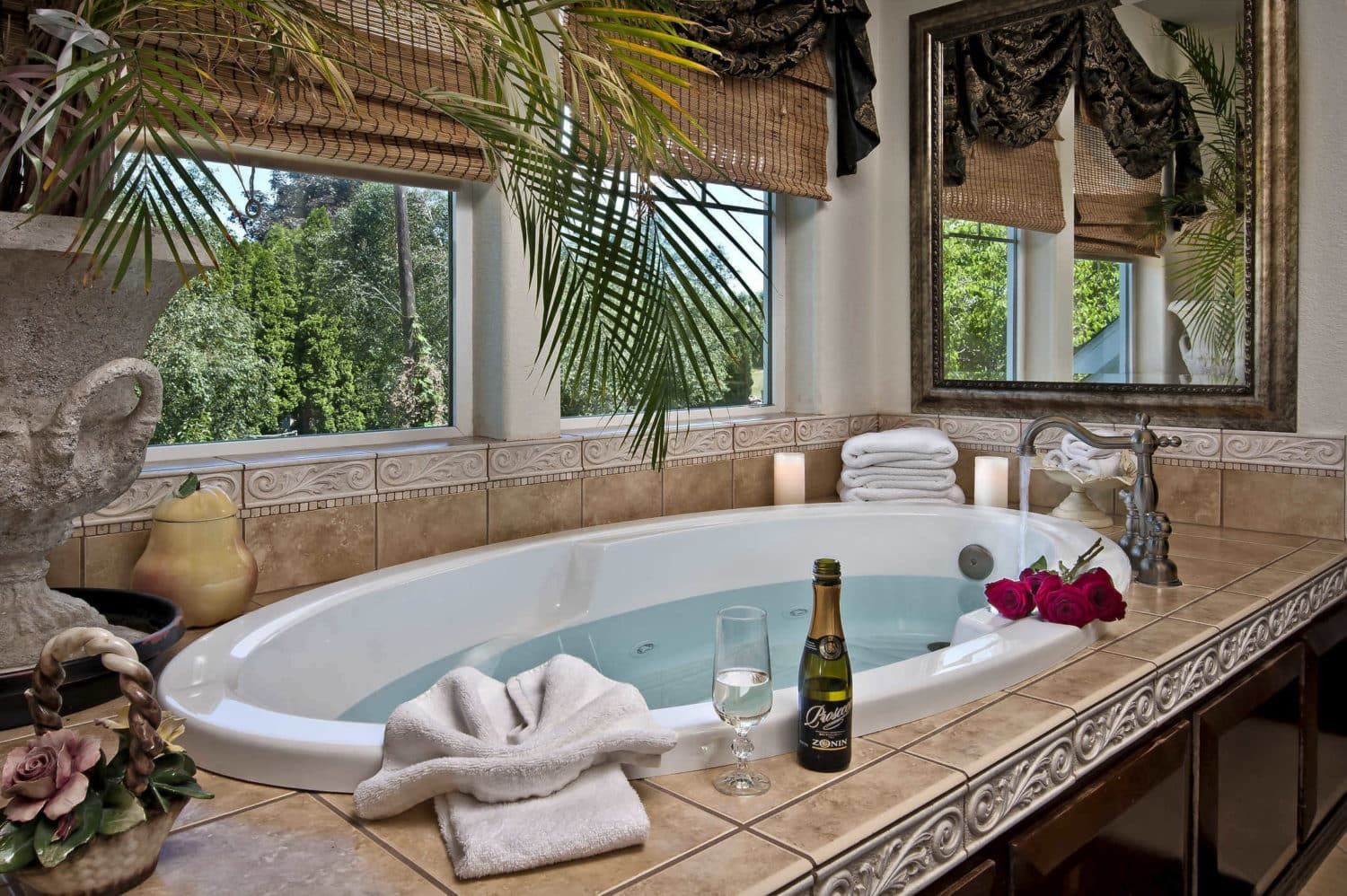 A bathtub in a bathroom with a bottle of champagne on the counter.