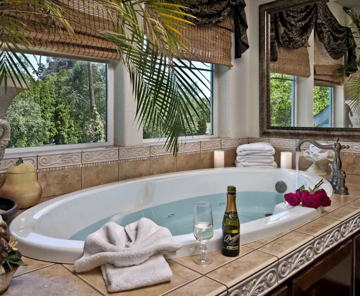 A bathroom with a jacuzzi tub and a bottle of champagne on the counter.