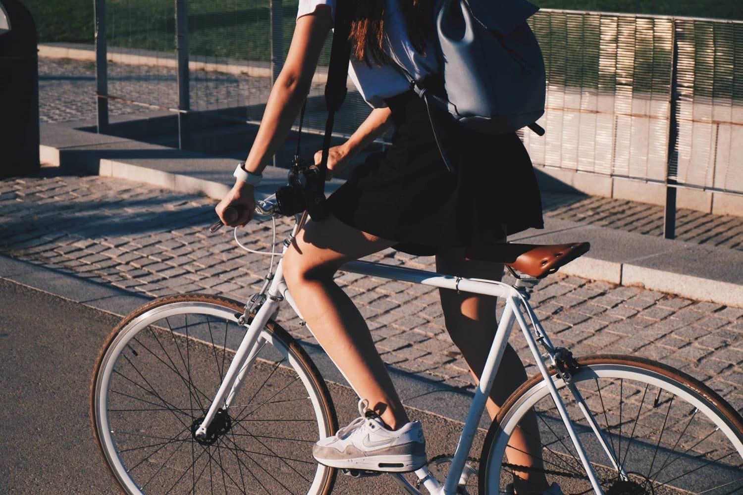 A woman with a backpack is riding a bike down a street.