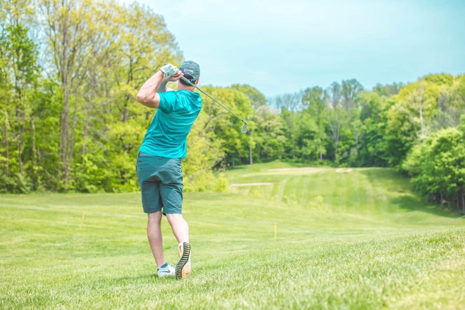 A man is swinging a golf club on a golf course.