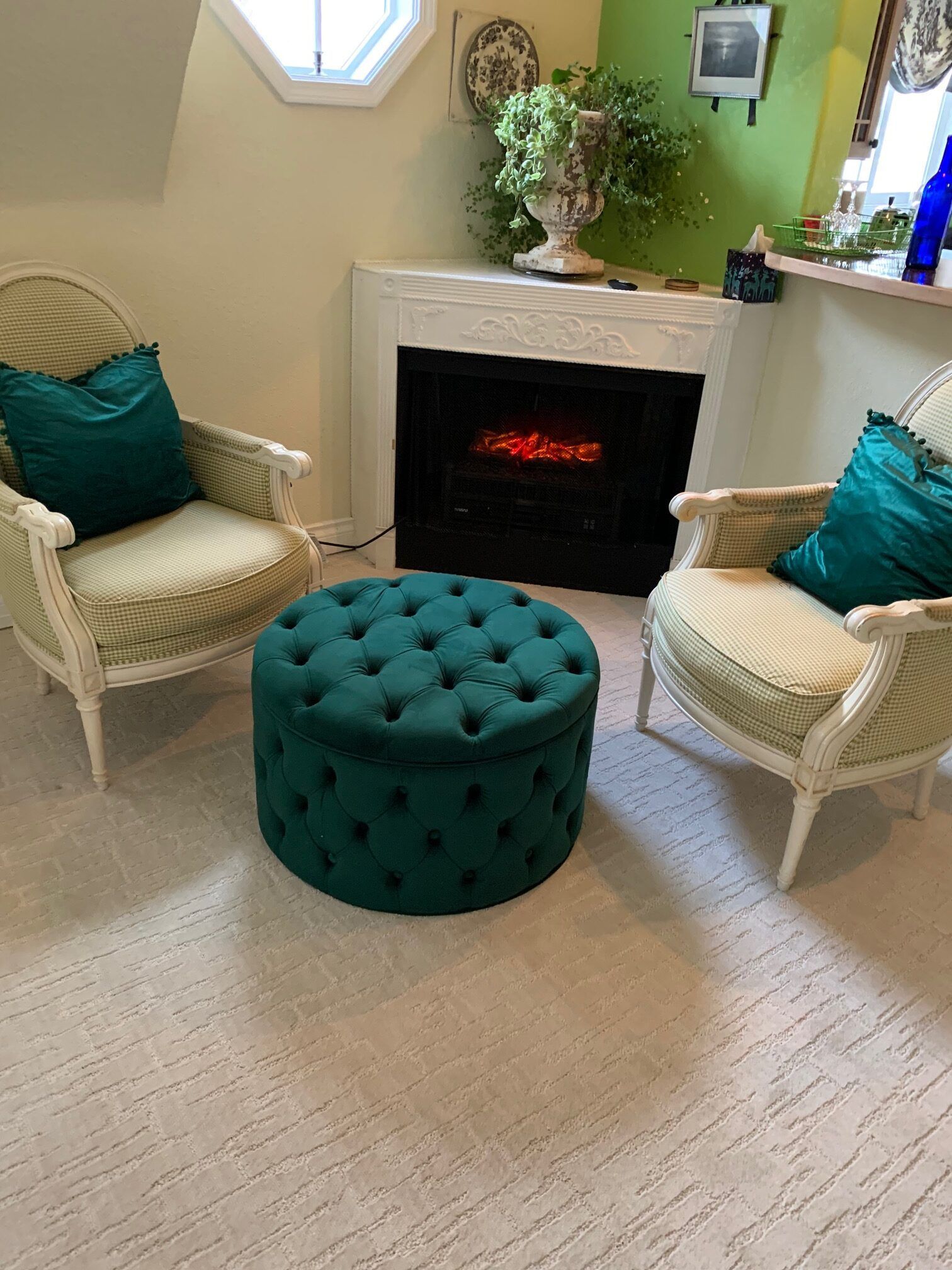 A living room with two chairs and an ottoman in front of a fireplace.