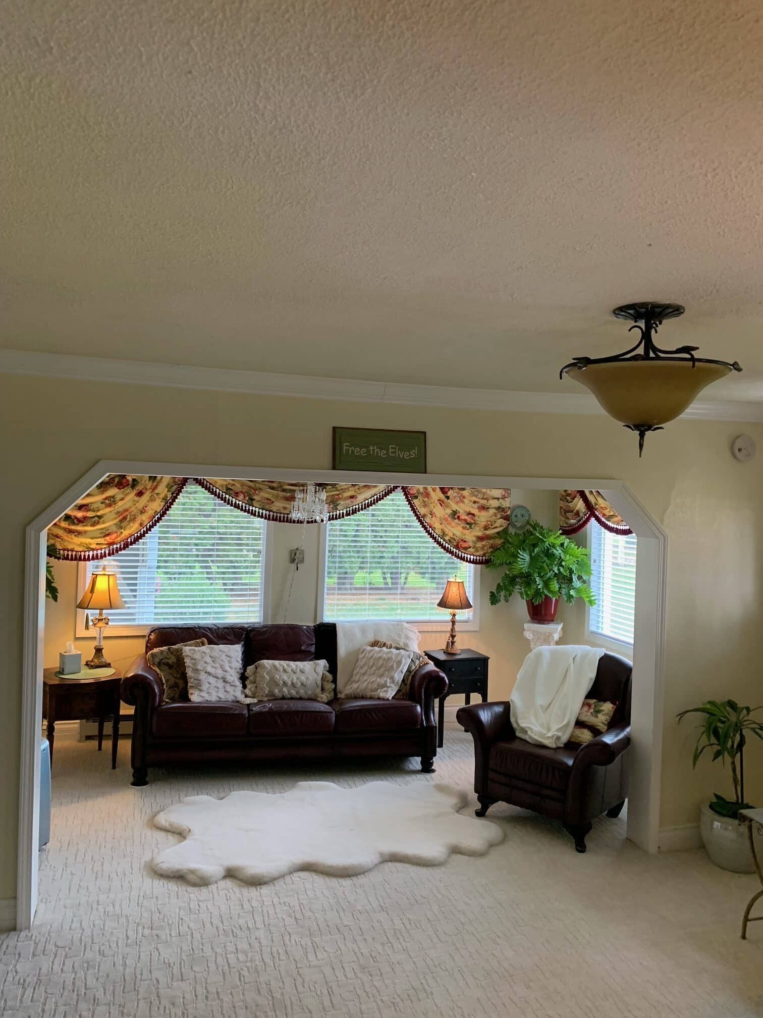 A living room with a brown couch and a white rug
