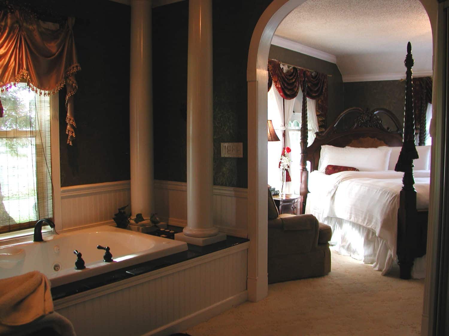 A bedroom with a four poster bed and a jacuzzi tub