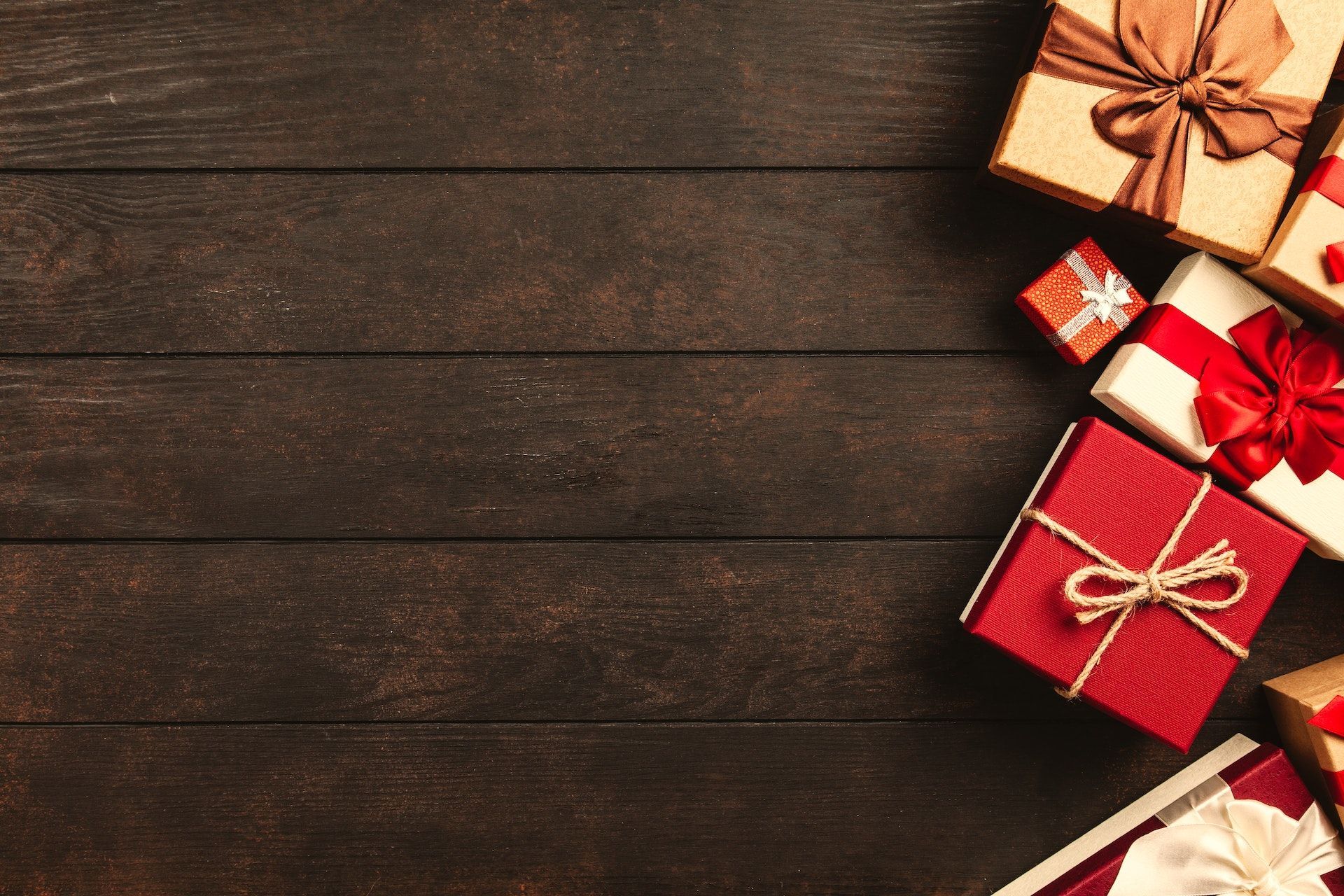 A pile of christmas presents on a wooden table.