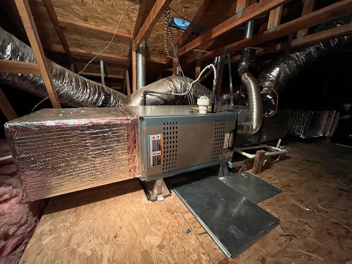 An air conditioner is sitting in the attic of a house.