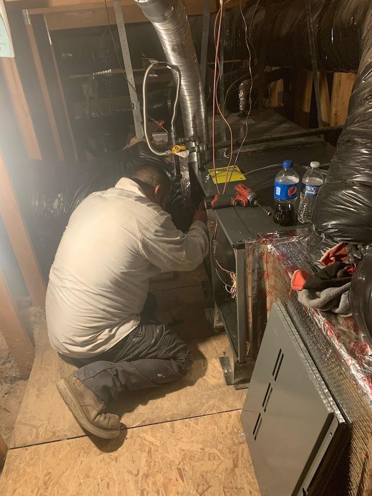 A man is kneeling down in a room working on a machine.