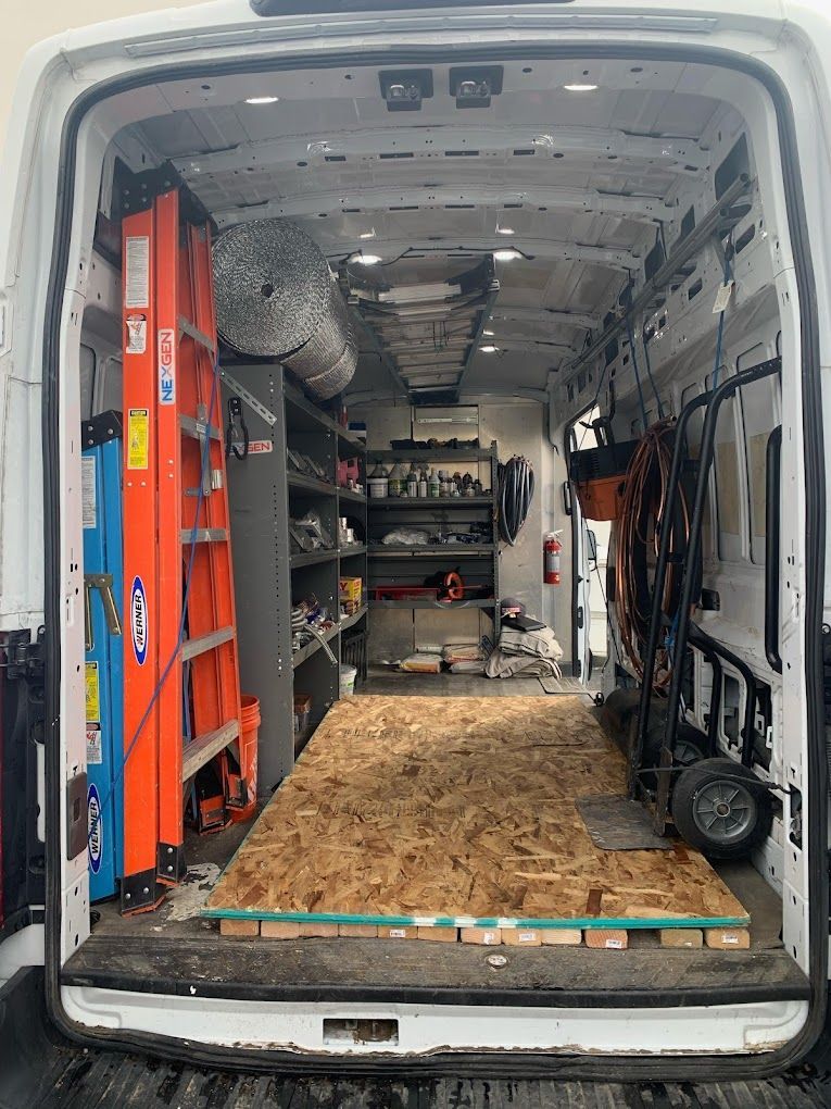 The inside of a van filled with tools and a ladder.