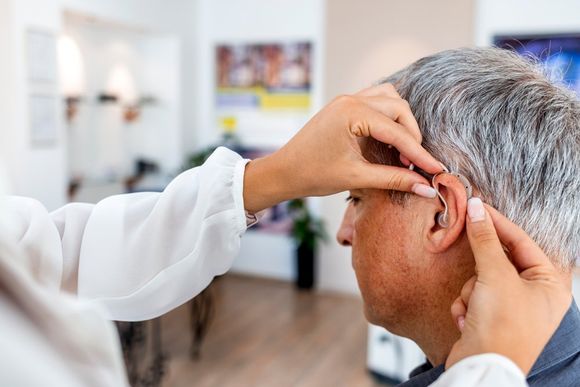 Doctor Fitting A Male Patient With A Hearing Aid — Belfast, ME — Hearing Solutions