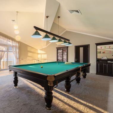 Elite Insta Bros Designs llc - Pool table in a brightly lit game room, with overhead lighting and a bar cabinet.