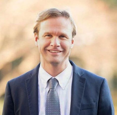 Jonathan Lee Stovall in a suit and tie is smiling for the camera.