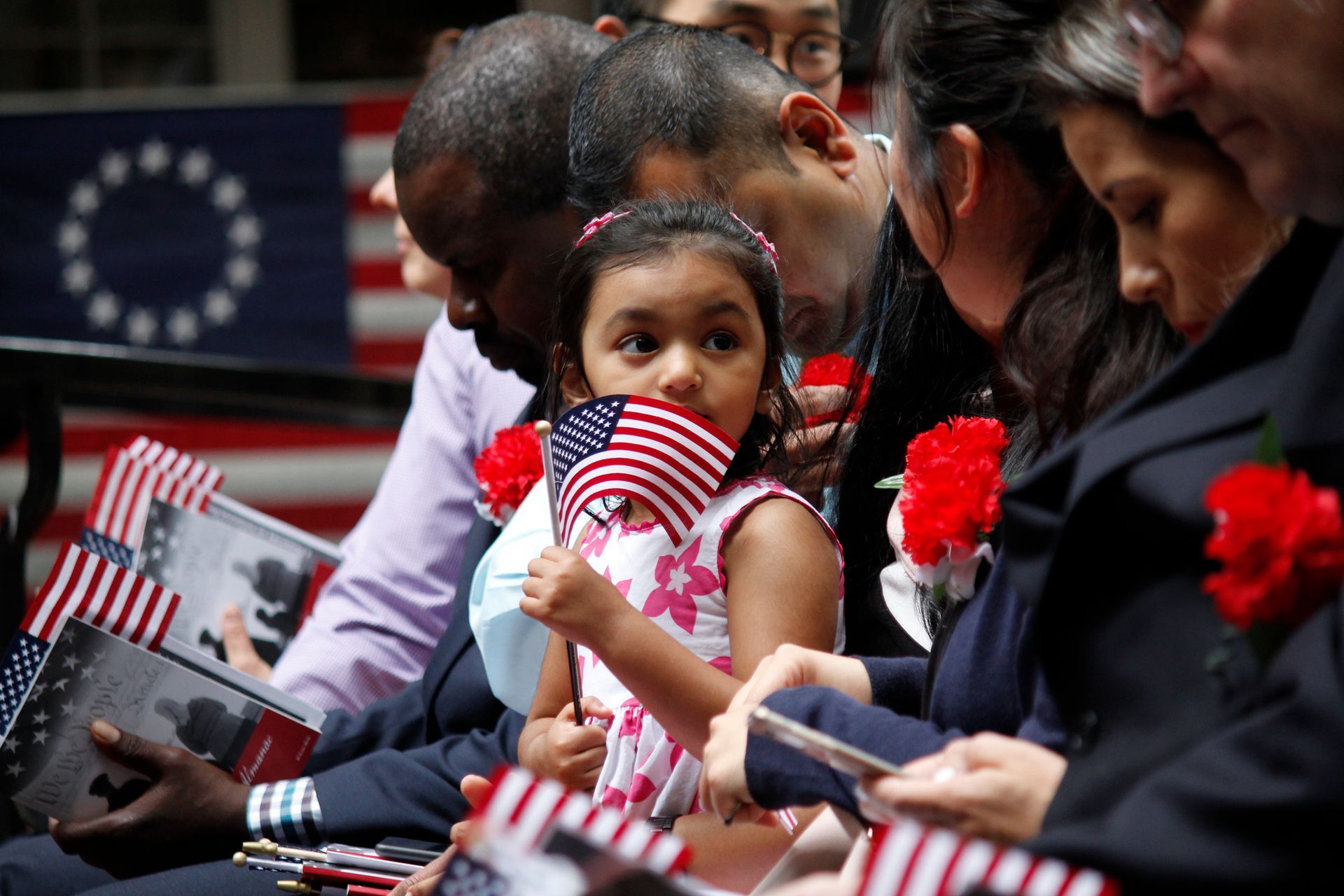 A little girl is holding an american flag in her hand