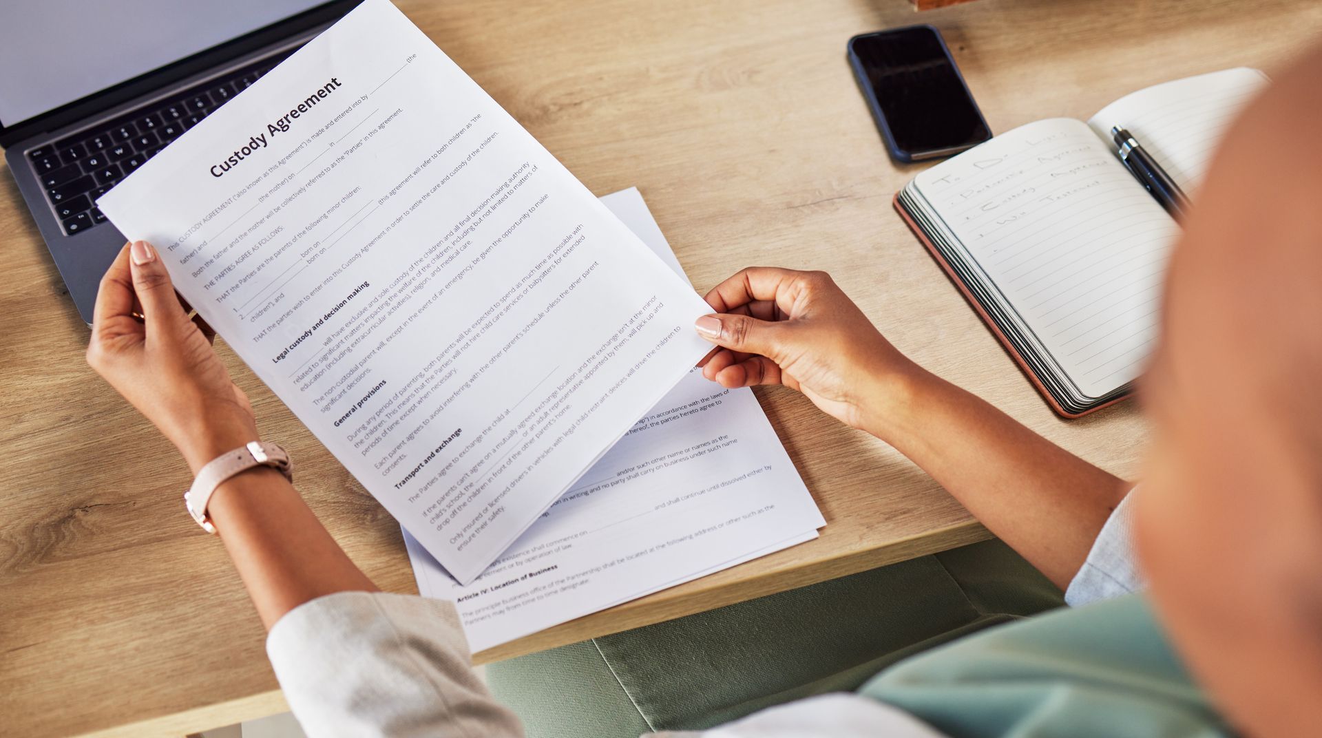 A woman is sitting at a desk holding a piece of paper.