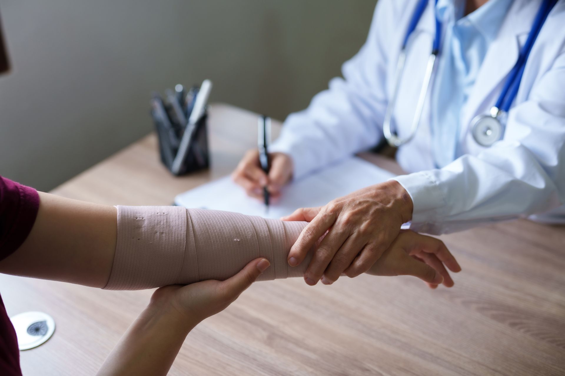 A doctor is examining a patient 's arm with a bandage on it.