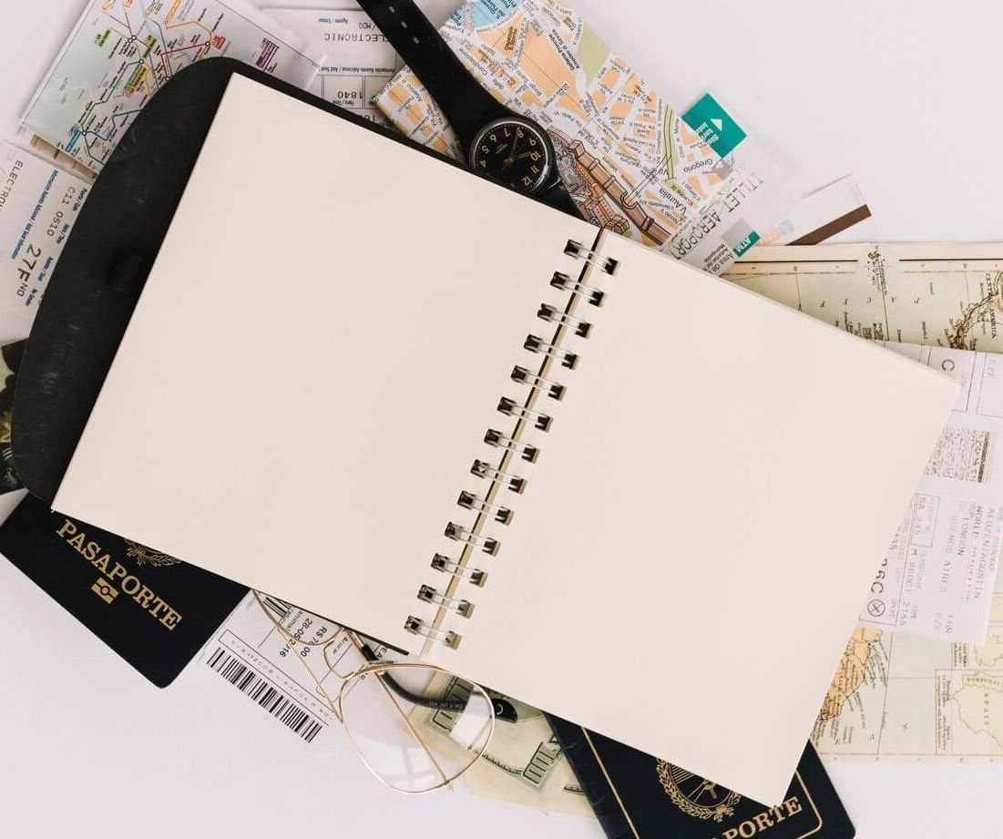 Un cuaderno está encima de una pila de pasaportes y billetes.
