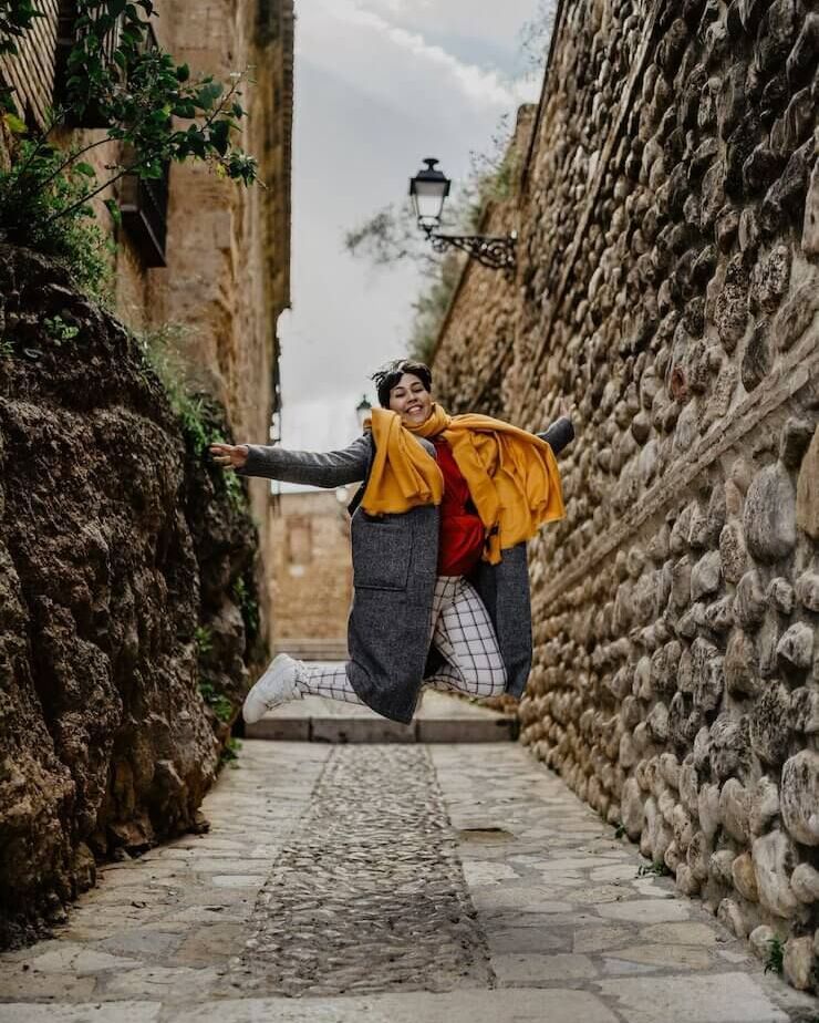 Una mujer está saltando en el aire en un callejón estrecho.